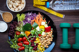 Insalata di verdure fresche, bottiglietta di acqua, pesi per esercizio fisico, metro per controllo di peso e altezza