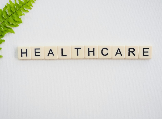 Tessere con la scritta HEALTHCARE su sfondo chiaro con foglia verde nell’angolo, immagine simbolica dedicata al settore sanitario.