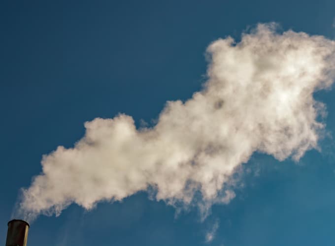 Camino industriale che rilascia fumo bianco nell’aria