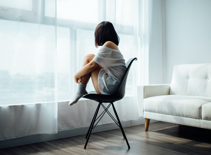donna seduta sedia stanza con tende bianche